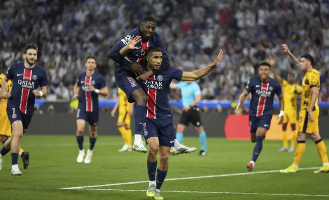 PSG's Achraf Hakimi celebrates with Ousmane Dembele after scoring his side's first goal during the Champions League final soccer match between Paris Saint-Germain and Inter Milan at the Allianz Arena in Munich, Germany, Saturday, May 31, 2025. (AP Photo/Matthias Schrader)