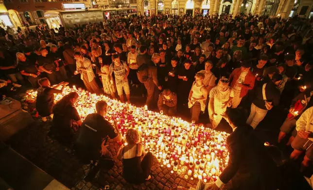 People light candles on the main square in the city center after a deadly shooting at a school in Graz, Austria, Tuesday, June 10, 2025. (AP Photo/Heinz-Peter Bader)