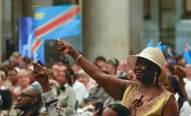 Faithful wave flags during a ceremony for the beatification of Floribert Bwana Chui Bin Kositi, a Congolese man killed in 2007 for fighting corruption, in St. Paul Outside the Walls' Basilica, in Rome, Sunday, June 15, 2025. (AP Photo/Riccardo De Luca)