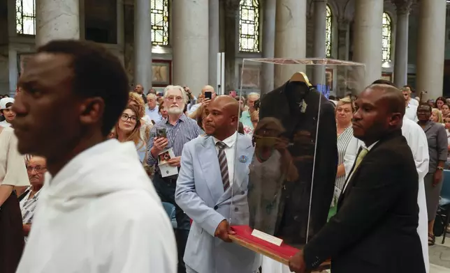 The jacket that Floribert Bwana Chui Bin Kositi was wearing at the time of his assassination is carried as a relic by his brothers Jean-Claude, left, and Trésor, at the start of a ceremony for his beatification in St. Paul Outside the Walls' Basilica, in Rome, Sunday, June 15, 2025. (AP Photo/Riccardo De Luca)