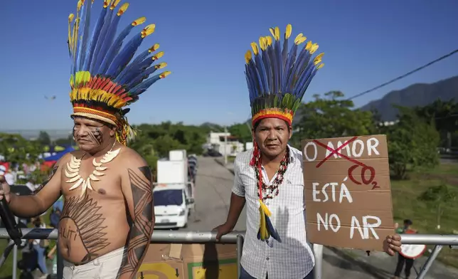 Indigenous demonstrators holds a sign that reads in Portuguese "Love, CO2 is in the air" to protest the auction of dozens of oil blocks, including blocks near the mouth of the Amazon River, in Rio de Janeiro, Tuesday, June 17, 2025. (AP Photo/Silvia Izquierdo)
