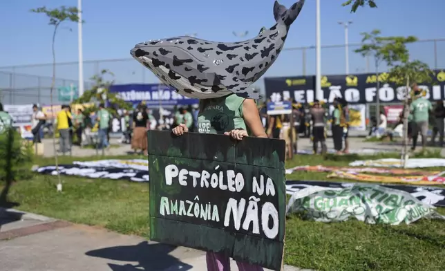 An protester wearing a whale mask holds a sign that reads in Portuguese, "No oil in the Amazon" to demonstrate against the auction of dozens of oil blocks, including blocks near the mouth of the Amazon River, in Rio de Janeiro, Tuesday, June 17, 2025. (AP Photo/Silvia Izquierdo