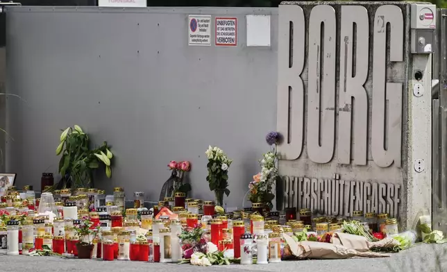 Flowers and candles are laid outside a school where a former student opened fire the day before fatally wounding several people and injuring many others before taking his own life, Graz, Austria, Wednesday, June 11, 2025. (AP Photo/Darko Bandic)