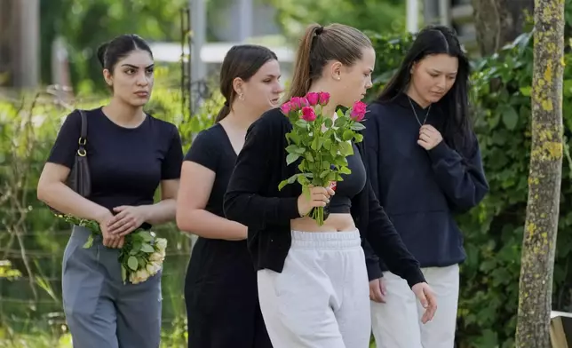 Women with flowers arrive at a school where a former student opened fire two days before, in Graz, Austria, Thursday, June 12, 2025. (AP Photo/Darko Bandic)