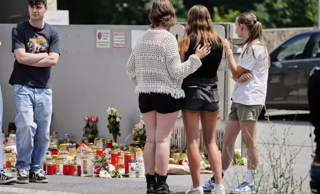Students stand outside a school where a former student opened fire the day before fatally wounding several people and injuring many others before taking his own life, Graz, Austria, Wednesday, June 11, 2025. (AP Photo/Darko Bandic)