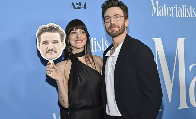 Dakota Johnson, left, and Chris Evans pose with a Pedro Pascal head cutout at the premiere of "Materialists" at the DGA New York Theater on Saturday, June 7, 2025, in New York. (Photo by Evan Agostini/Invision/AP)