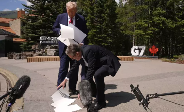 President Donald Trump drops papers as he meets with Britain's Prime Minister Keir Starmer on the sidelines of the G7 Summit, Monday, June 16, 2025, in Kananaskis, Canada. (AP Photo/Mark Schiefelbein)