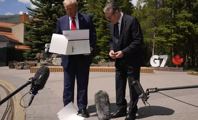 President Donald Trump drops papers as he meets with Britain's Prime Minister Keir Starmer on the sidelines of the G7 Summit, Monday, June 16, 2025, in Kananaskis, Canada. (AP Photo/Mark Schiefelbein)