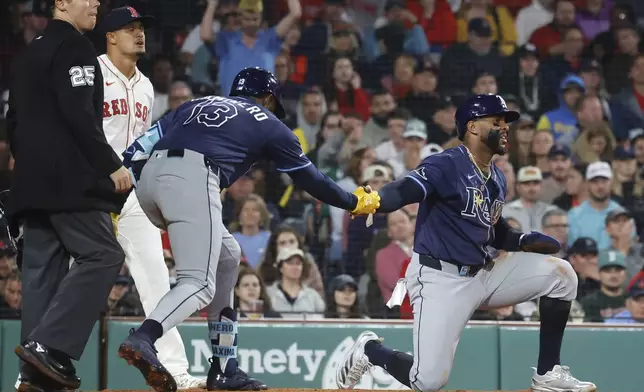 Tampa Bay Rays' Yandy Díaz is congratulated by teammate Junior Caminero (13) after scoring on a single by Jonathan Aranda during the seventh inning of a baseball game against the Boston Red Sox at Fenway Park, Monday, June 9, 2025, in Boston. (AP Photo/Mary Schwalm)