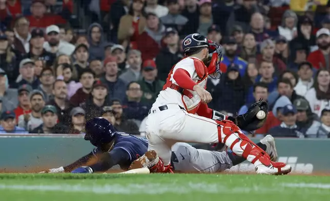 Tampa Bay Rays' Yandy Díaz slides into home ahead of the tag from Boston Red Sox catcher Connor Wong (12) to score on a single by Jonathan Aranda during the seventh inning of a baseball game at Fenway Park, Monday, June 9, 2025, in Boston. (AP Photo/Mary Schwalm)