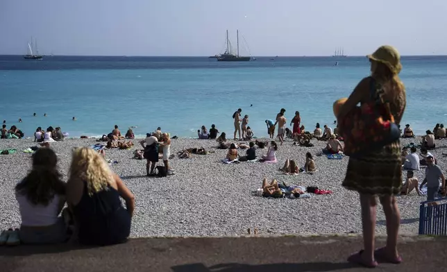 People enjoy the beach as vessels sail during the "Ocean Wonders" themed event in honor of World Oceans Day ahead of the U.N. Ocean Conference on Sunday, June 8, 2025, in Nice, France. (AP Photo/Annika Hammerschlag)