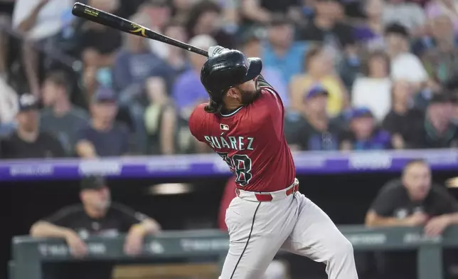 Arizona Diamondbacks' Eugenio Suárez follows the flight of his two-run home run off Colorado Rockies relief pitcher Ryan Rolison in the sixth inning of a baseball game Friday, June 20, 2025, in Denver. (AP Photo/David Zalubowski)