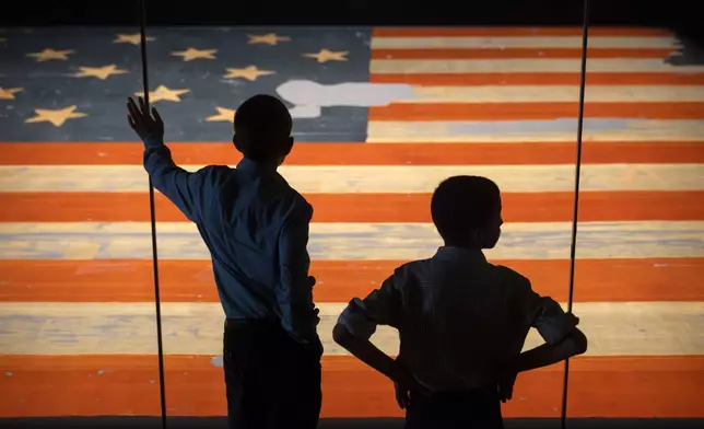 Children look at the Star Spangled Banner, the flag that inspired the lyrics of the American national anthem, at the Smithsonian's National Museum of American History, Tuesday, June 10, 2025, in Washington. (AP Photo/Mark Schiefelbein)