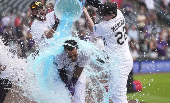 Colorado Rockies' Orlando Arcia, center, is doused by Sam Hilliard, left, and Mickey Moniak, right, after his walkoff single to drive in two runs to defeat the San Francisco Giants in a baseball game Thursday, June 12, 2025, in Denver. (AP Photo/David Zalubowski)
