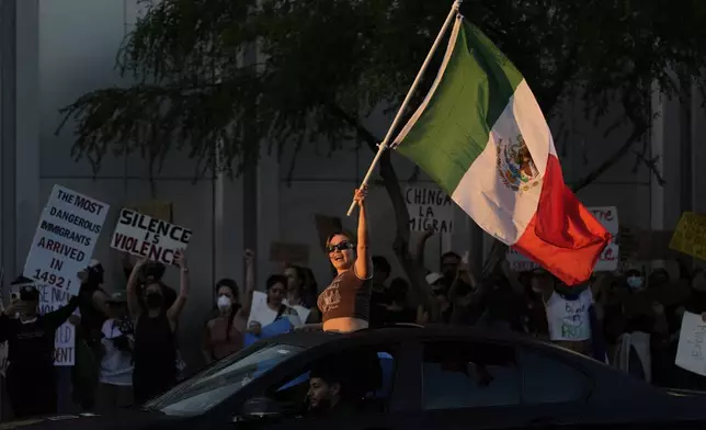 A woman waves a Mexican flag during protests over President Donald Trump's stepped-up enforcement of immigration laws, Wednesday, June 11, 2025, in Las Vegas. (AP Photo/John Locher)
