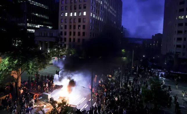 Protestors surround a dumpster that was set on fire in front of the Henry M. Jackson Federal Building during a protest against federal immigration arrests, Wednesday, June 11, 2025, in Seattle. (AP Photo/Ryan Sun)