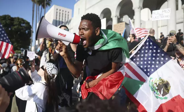A man shouts into a megaphone outside City Hall during a protest on Wednesday, June 11, 2025, in Los Angeles. (AP Photo/Ethan Swope)