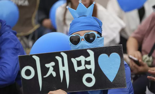 A supporter of South Korea's Democratic Party's presidential candidate Lee Jae-myung, holds a sign reading " Lee Jae-myung" during a presidential election campaign in Seoul, South Korea, Monday, June 2, 2025. (AP Photo/Lee Jin-man)