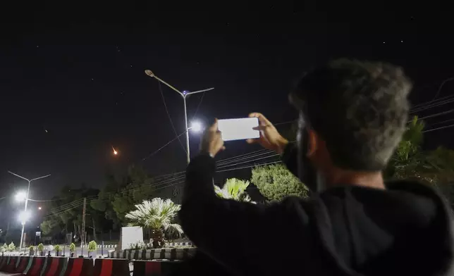 A Syrian man takes pictures with his mobile phone of Iranian missiles on their way toward Israel, as they pass over Damascus airspace, Syria, Friday, June 13, 2025. (AP Photo/Omar Sanadiki)