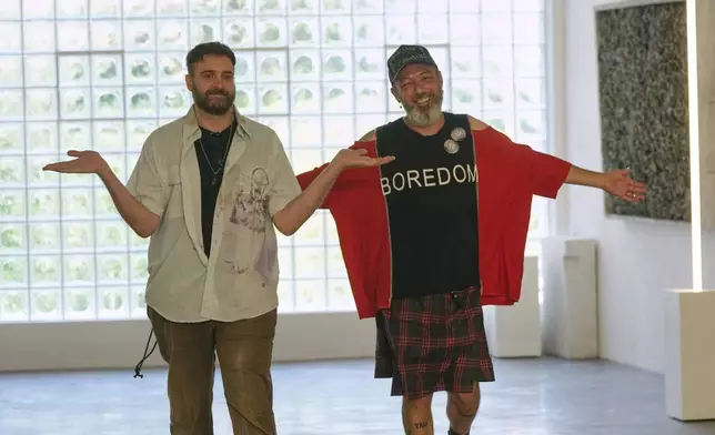 Designers Simone Botte, left, and Filippo Biraghi accept applause after the conclusion of the men's Simon Cracker Spring-Summer 2026 collection, that was presented in Milan, Italy, Sunday, June 22, 2025. (AP Photo/Luca Bruno)