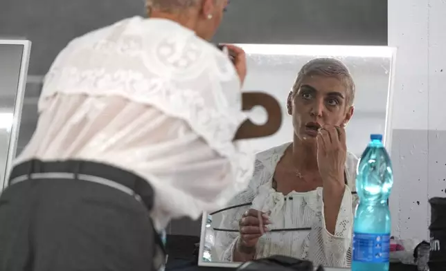 A model adjusts her make up backstage prior to the men's Simon Cracker Spring-Summer 2026 collection, that was presented in Milan, Italy, Sunday, June 22, 2025. (AP Photo/Luca Bruno)