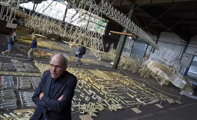 Dutch artist Theo Jansen is interviewed in front of his 'strandbeesten' or Beach Beasts, wind-powered creatures made from yellow plastic tubes, displayed during an exhibit in Delft, Netherlands, Thursday, June 5, 2025. (AP Photo/Peter Dejong)