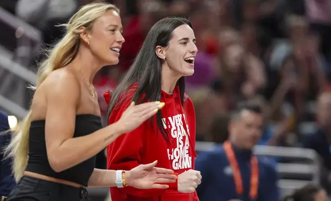 Indiana Fever guard Caitlin Clark, right, and guard Sophie Cunningham celebrates on the bench in the first half of a WNBA basketball game against the Washington Mystics in Indianapolis, Tuesday, June 3, 2025. (AP Photo/Michael Conroy)