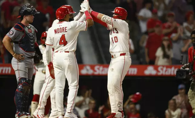 Los Angeles Angels' Kevin Newman, right, celebrates with teammates after hitting a three-run home run during the seventh inning of a baseball game against the Washington Nationals, Saturday, June 28, 2025, in Anaheim, Calif. (AP Photo/William Liang)