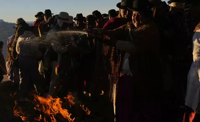 An Andean religious leader sprinkles liquor into a bonfire during the Andean New Year of 5,533 celebration in El Alto, Bolivia, Saturday, June 21, 2025. (AP Photo/Juan Karita)