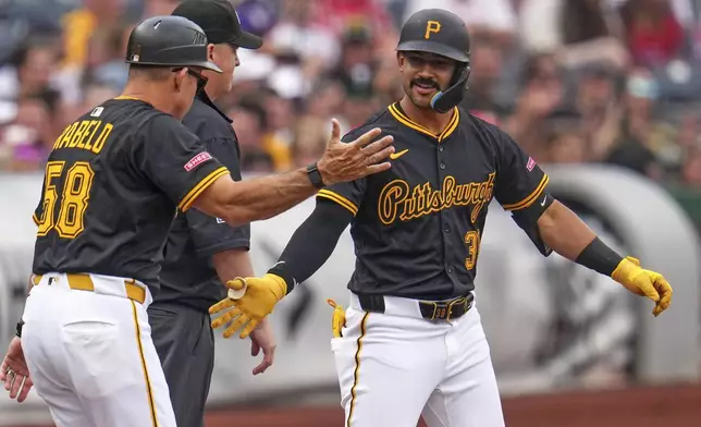 Pittsburgh Pirates' Nick Gonzales, right, with third base coach Mike Rabelo (58) after hitting a triple off Philadelphia Phillies pitcher Ranger Suárez during the first inning of a baseball game in Pittsburgh, Saturday, June 7, 2025. (AP Photo/Gene J. Puskar)