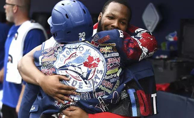 Toronto Blue Jays' Vladimir Guerrero Jr., right, celebrates in the dugout with Alejandro Kirk (30) after Kirk's solo home run against the Arizona Diamondbacks in second-inning baseball game action in Toronto, Thursday, June 19, 2025. (Jon Blacker/The Canadian Press via AP)