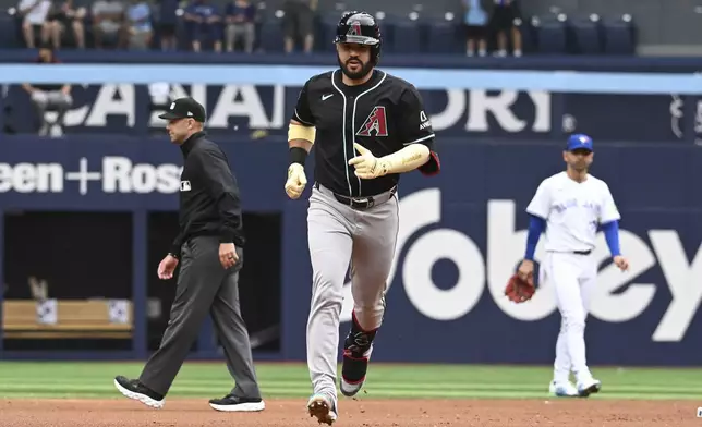 Arizona Diamondbacks' Eugenio Suarez, center, runs the bases after hitting a two-RBI home run against the Toronto Blue Jays in second-inning baseball game action in Toronto, Thursday, June 19, 2025. (Jon Blacker/The Canadian Press via AP)