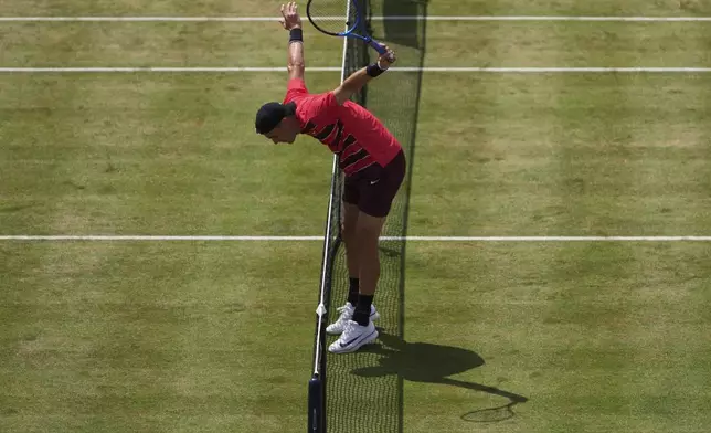 Britain's Jack Draper tries to prevent himself from from running into the net after returning to Jenson Brooksby of the United States during their men's singles match at the Queen's Club grass court tennis championships in London, Tuesday, June 17, 2025. (AP Photo/Joanna Chan)