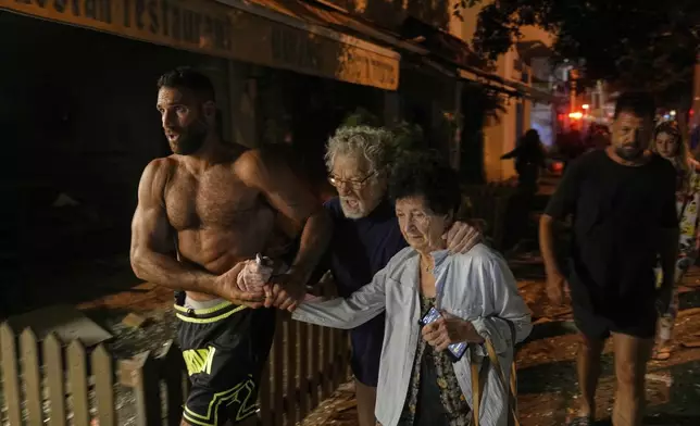People evacuate after a missile launched from Iran struck Tel Aviv, Israel, Monday June 16, 2025. (AP Photo/Baz Ratner)