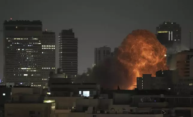 An explosion is seen during a missile attack in Tel Aviv, Israel, Sunday, June 15, 2025. (AP Photo/Leo Correa)