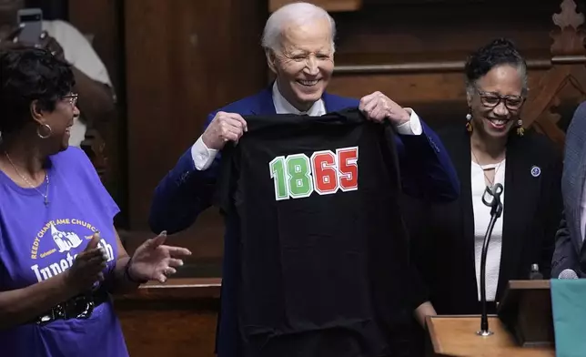 Former President Joe Biden holds up a T-shirt designed with the date 1865 during a Juneteenth event at the Reedy Chapel AME Church, Thursday, June 19, 2025, in Galveston, Texas. (AP Photo/David J. Phillip)