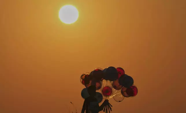 A boy sells balloons as the sun sets over the Mediterranean Sea in Beirut, Tuesday, June 17, 2025. (AP Photo/Bilal Hussein)