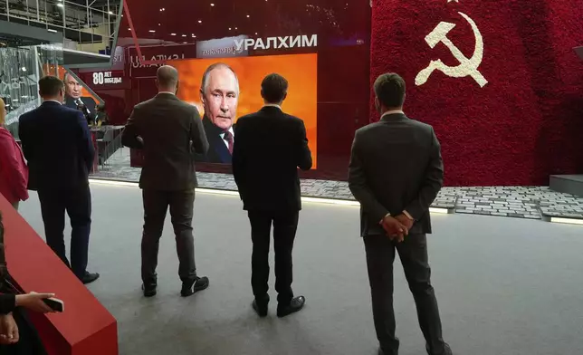 Participants watch a broadcast of Russian President Vladimir Putin's speech on a TV screen during a plenary session of the St. Petersburg International Economic Forum in St. Petersburg, Russia, Friday, June 20, 2025. (AP Photo/Dmitri Lovetsky)