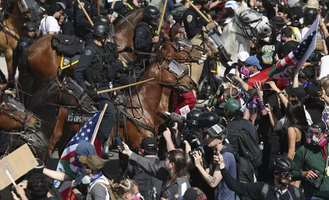 Demonstrators standoff against law enforcement on horseback during a protest Saturday, June 14, 2025, in Los Angeles. (AP Photo/Ethan Swope)