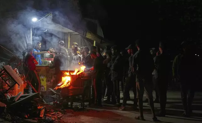 Palestinians line up to buy dinner at a food stand near the beachfront at a tent camp for displaced people in the Gaza City port, Saturday, June 14, 2025. (AP Photo/Jehad Alshrafi)