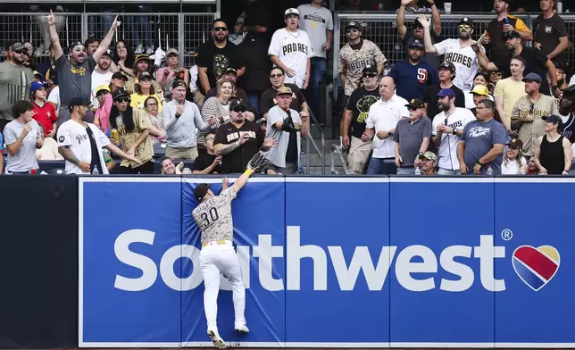 San Diego Padres left fielder Gavin Sheets (30) attempts to catch a fly ball at the wall hit by Pittsburgh Pirates' Adam Frazier in the fourth inning of a baseball game Sunday, June 1, 2025, in San Diego. (AP Photo/Derrick Tuskan)