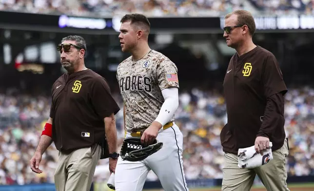 San Diego Padres' Gavin Sheets, center, walks off the field with members of the training staff after running into the wall in the fourth inning of a baseball game against the Pittsburgh Pirates, Sunday, June 1, 2025, in San Diego. (AP Photo/Derrick Tuskan)