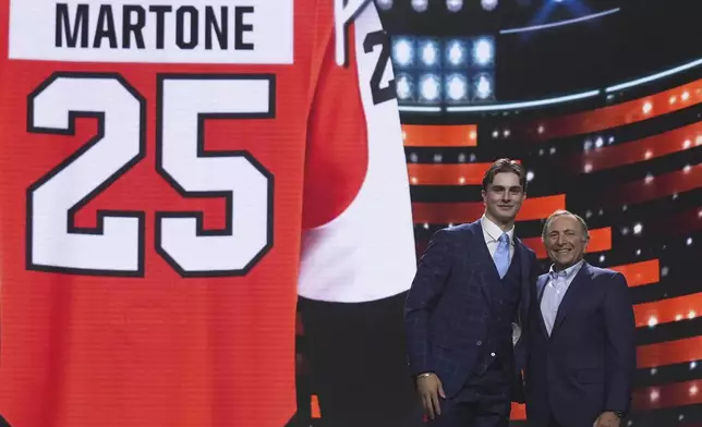 Porter Martone, second from right, stands next to NHL commissioner Gary Bettman after being drafted by the Philadelphia Flyers during the NHL hockey draft Friday, June 27, 2025, in Los Angeles. (AP Photo/Damian Dovarganes)