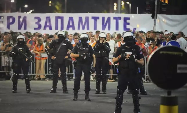 Riot police take positions between government supporters, seen in the background, and people taking part in a major anti-government rally pressing for an early election after nearly eight months of almost daily anti-corruption demonstrations that have shaken the populist government of President Aleksandar Vucic, in Belgrade, Serbia, Saturday, June 28, 2025. (AP Photo/Darko Vojinovic)