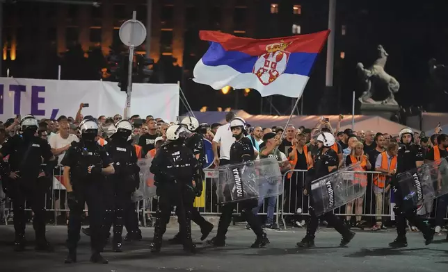 Riot police take positions between government supporters, seen in the background, and people taking part in a major anti-government rally pressing for an early election after nearly eight months of almost daily anti-corruption demonstrations that have shaken the populist government of President Aleksandar Vucic, in Belgrade, Serbia, Saturday, June 28, 2025. (AP Photo/Darko Vojinovic)