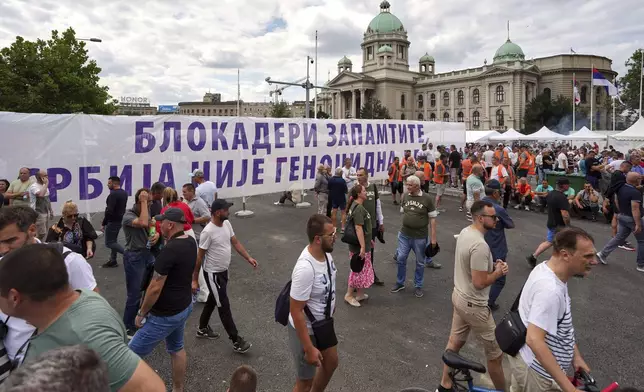 Government supporters gather hold a banner that reads "Blockaders - Remember - Serbia is not a genocidal state" outside the Parliament building ahead of a major anti-government rally pressing for an early election after nearly eight months of almost daily anti-corruption demonstrations that have shaken the populist government of President Aleksandar Vucic, in Belgrade, Serbia, Saturday, June 28, 2025. (AP Photo/Darko Vojinovic)