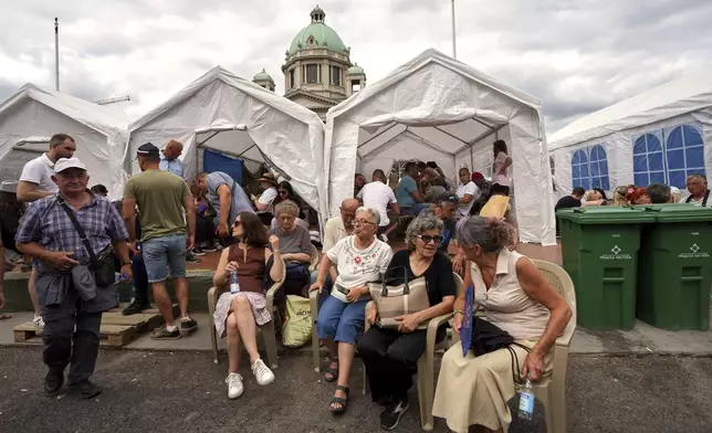 Government supporters gather outside the Parliament building ahead of a major anti-government rally pressing for an early election after nearly eight months of almost daily anti-corruption demonstrations that have shaken the populist government of President Aleksandar Vucic, in Belgrade, Serbia, Saturday, June 28, 2025. (AP Photo/Darko Vojinovic)