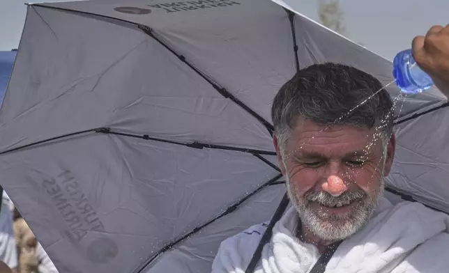 A pilgrim receives water to cool himself at the rocky hill known as the Mountain of Mercy, on the Plain of Arafat, during the annual Hajj pilgrimage near the holy city of Mecca, Saudi Arabia, Thursday, June 5, 2025. (AP Photo/Amr Nabil)