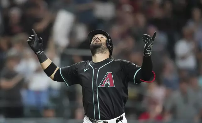 Arizona Diamondbacks' Eugenio Suárez looks up as he arrives at home plate after hitting a grand slam against the Seattle Mariners during the sixth inning of a baseball game Wednesday, June 11, 2025, in Phoenix. (AP Photo/Ross D. Franklin)