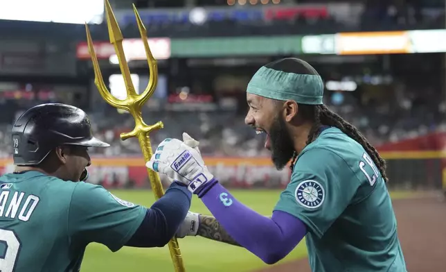 Seattle Mariners' Donovan Solano, left, celebrates his home run against the Arizona Diamondbacks with Mariners' J.P. Crawford during the fifth inning of a baseball game Wednesday, June 11, 2025, in Phoenix. (AP Photo/Ross D. Franklin)